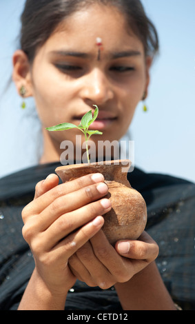 Teenage girl holding indienne des semis d'une plante dans un pot en argile. L'Inde Banque D'Images