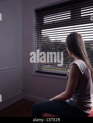 Vue arrière d'une jeune femme rêveuse assise seule à la recherche d'une fenêtre. Banque D'Images