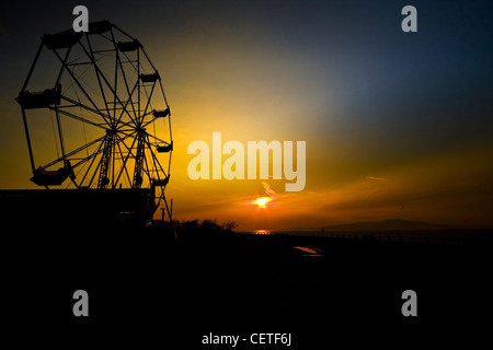 La silhouette d'une grande roue au coucher du soleil à Silloth. Banque D'Images