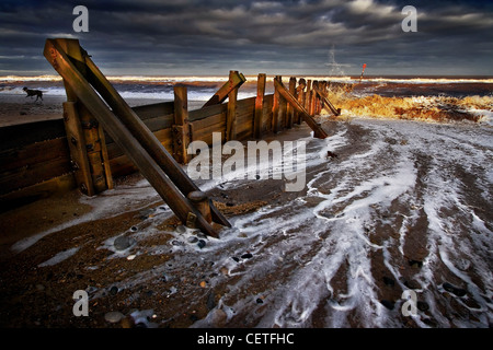 Vagues se briser contre l'eau côtière sous des nuages sombres à disjoncteur Hornsea. Banque D'Images