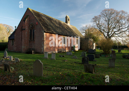 L'église en brique rouge peu étrange de l'Ascension, et c'est cimetière, dans le village de Dorset de Woodlands. Angleterre, Royaume-Uni. Banque D'Images