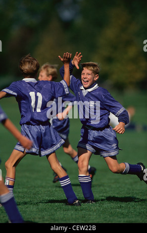 Les garçons de 11 ans, joueur de football célèbre un but. Banque D'Images