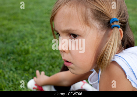 Fillette de six ans assis dans l'herbe à la grave Banque D'Images