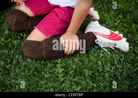 Enfant portant Soccer Cleats assis dans l'herbe Banque D'Images