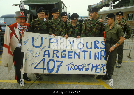 Guerre des Malouines les soldats britanniques attendent de partir de Southampton sur le QE2 avec un homme mascotte portant un drapeau de la croix rouge de St George sur fond blanc et portant un chapeau haut de forme. Circa mai 1982. Soldats tenant une bannière, Up Yours Argentina 407 troupes ici. Ils faisaient partie de la '407 Road transport Troop' du Royal corps of transport. Années 1980 Royaume-Uni. HOMER SYKES Banque D'Images