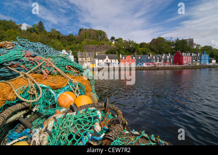 Filets de pêche colorés empilés devant une terrasse de maisons colorées dans le port de Tobermory sur l'île de Mull Banque D'Images