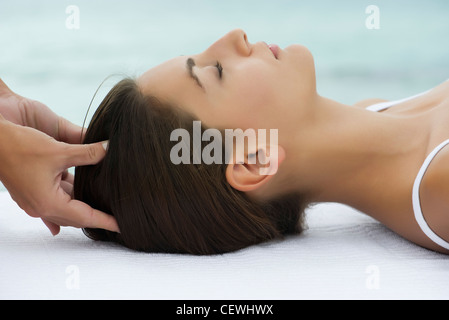 Young woman receiving massage de la tête, vue de côté Banque D'Images