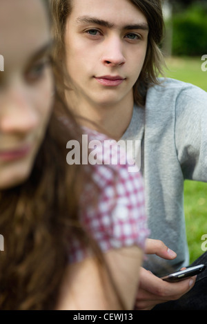 Jeune homme tenant téléphone texte, portrait Banque D'Images