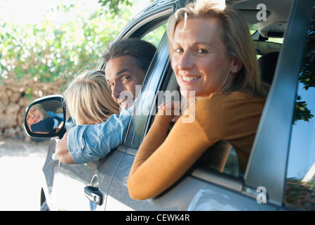 Famille ensemble en voiture, penché sur les épaules de windows et smiling at camera Banque D'Images