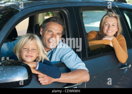 Famille ensemble en voiture, penché windows and smiling at camera Banque D'Images