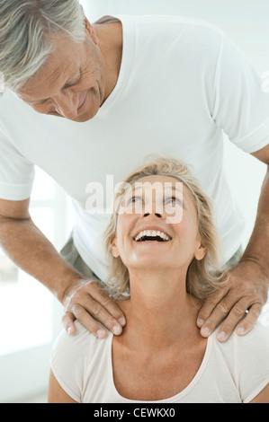 Mature couple smiling at each other comme les épaules de l'homme femme massages Banque D'Images