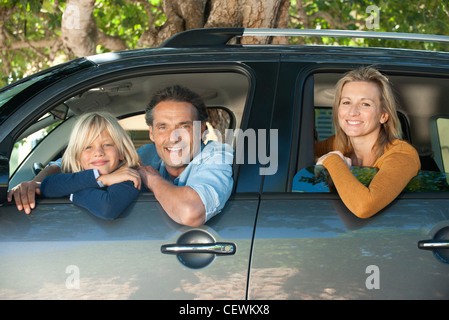 Famille ensemble en voiture, penché windows and smiling at camera Banque D'Images