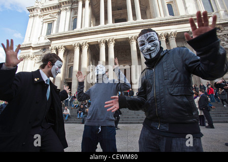 Des manifestants masqués anonymes de UK à Occupy London OSLX protester, danse en face de la Cathédrale St Paul, à Londres. Banque D'Images