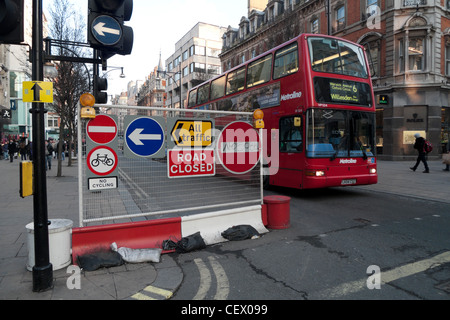 Des signes de contrôle de la circulation sur une section fermée d'Oxford Street et d'un bus à impériale rouge West End London England UK Banque D'Images