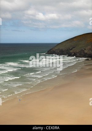 Surfers carrying leurs planches de la mer sur la plage de sable entre Newquay et Mawgan Porth sur la côte de Cornouailles. Banque D'Images