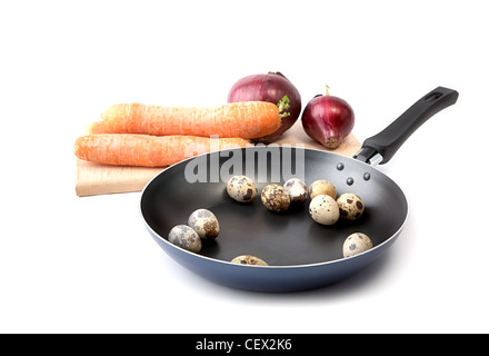 Les carottes, les oignons sur une planche à découper et des oeufs de cailles sur poêle Banque D'Images