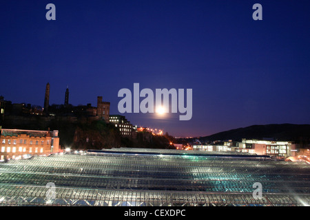 Vue sur la gare de Waverley Bridge North skyline à Calton Hill grande lune ciel nuit rétroéclairé bleu foncé toit en verre Banque D'Images