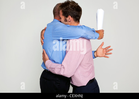 Photo de deux hommes d'étreindre chacun ayant un contrat, partie d'une série voir mon portefeuille pour se battre. Banque D'Images