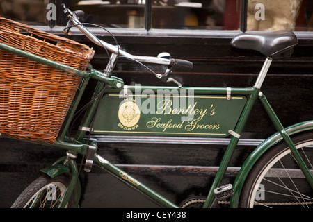 Vue d'un vieux vélo traditionnel avec un panier en osier à l'extérieur de la mer restaurant épiciers Bentley Banque D'Images