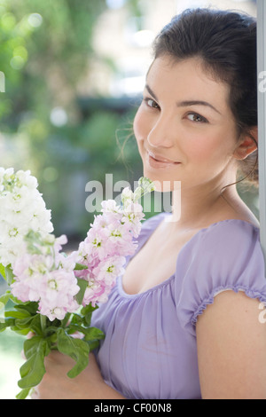 Attacher les cheveux ondulés femelle brune à l'arrière, portant un haut de lilas blanc et rose, fleurs, smiling, looking at camera Banque D'Images