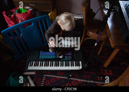 Un enfant marche sur le matériel de musique de ses parents, un clavier et une boîte à rythme. Banque D'Images