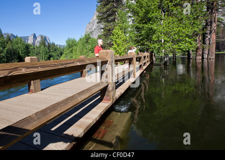 Les touristes, debout sur Swinging Bridge à peine au-dessus de la rivière Merced à l'étape d'inondation - Yosemite National Park, Californie Banque D'Images