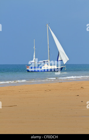 Yacht bleu ancré près de la plage de sable Banque D'Images