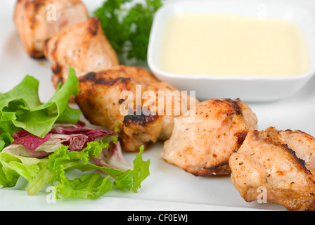 Brochette de poulet grillées avec sauce et verts on white plate Banque D'Images