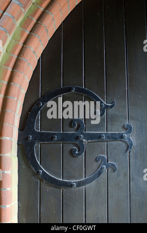 Charnière en fer forgé décoratif sur la porte extérieure d'une chapelle dans le cimetière de Wymondham, Norfolk, East Anglia, Angleterre, Royaume-Uni. Banque D'Images