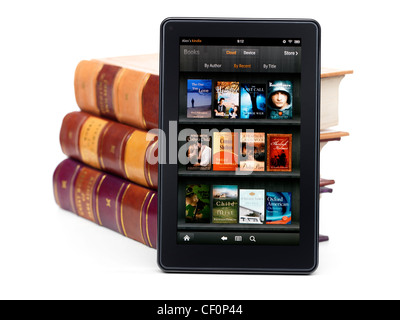 Amazon Kindle Fire tablet computer e-book reader appuyé contre une pile de livres à couverture rigide. Isolé sur fond blanc. Banque D'Images