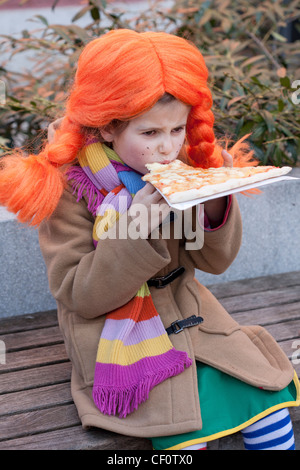 Petite fille habillée comme Pippi longues stocking de manger des pizzas. Banque D'Images