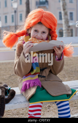 Petite fille habillée comme Pippi longues stocking de manger des pizzas. Banque D'Images