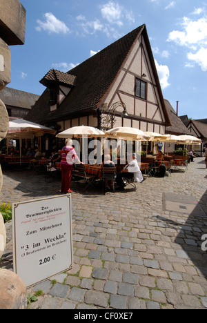 Les visiteurs déjeunent au restaurant Bratwurstglocklein, dans le village médiéval du Handwerkerhof (cour des commerçants) à Nuremberg, en Allemagne. Banque D'Images