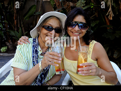 Mother and Daughter hugging avec bonheur et profiter des vacances avec des boissons fraîches dans le jardin à beach resort en Afrique du Sud. Banque D'Images
