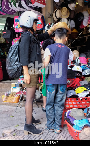 Femme casquée son fils d'acheter un chapeau, Hanoi, Vietnam, Asie du sud-est Banque D'Images