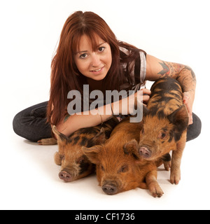 Une jeune femme dans la vingtaine, avec ses trois porcelets Kune Kune micro pet Banque D'Images