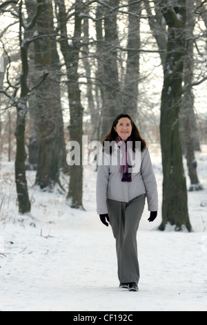 Femme d'âge moyen de marcher dans la neige Banque D'Images