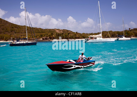 Un bateau à moteur local par le biais de croisières voiliers amarrés au large de l'île privée de Petit Saint Vincent, ou PSV. Banque D'Images