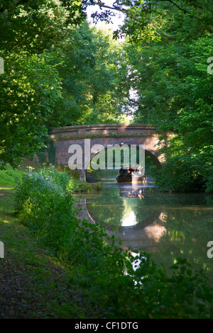 Un couple voyageant dans une barge sous un pont le long du canal de Kennet et Avon près de Burbage quai. Banque D'Images