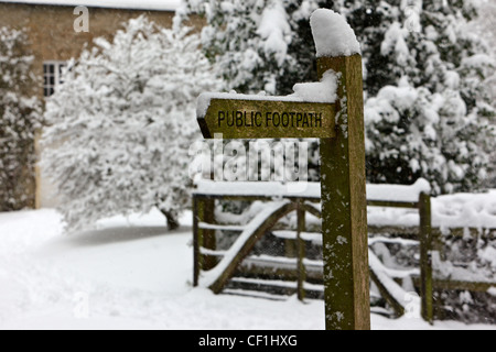 La neige sur le haut d'un sentier public signe dans un village d'hiver enneigé. Banque D'Images