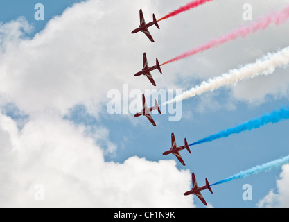 Cinq des flèches rouges en formation lors d'un défilé avec rouge, blanc et bleu de traînées de fumée. Banque D'Images