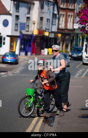 Une grand-mère et son petit-fils en poussant leur vélo à travers une route dans la région de Abingdon. Banque D'Images