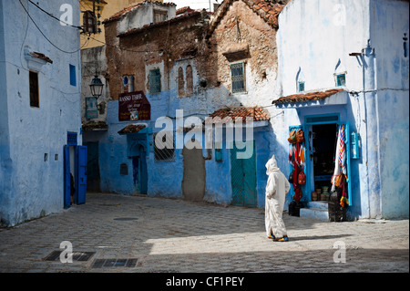 Muslim man walking in the blue remparts de la vieille médina de Chefchaouen, Maroc Banque D'Images