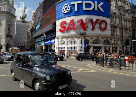 London Taxis roulant au-delà de la célèbre grande publicité dans Piccadilly Circus. Banque D'Images