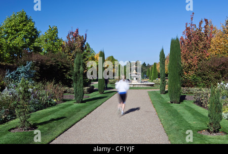 Une femme le jogging à travers les jardins paysagers à Regent's Park. Banque D'Images