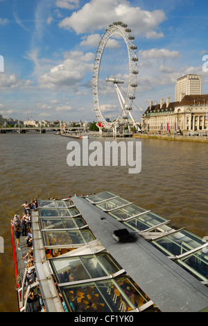 Un bateau se déplaçant le long de la Tamise vers le London Eye. Banque D'Images