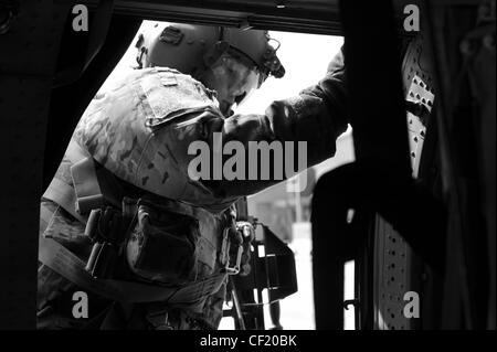 Un MEMBRE de l'équipage UH-60 Black Hawk affecté à UN talon de la Force opérationnelle aérienne 3-82 à l'aéroport de Bagram, se prépare au décollage le 25 février 2012. L'unité effectue des missions de circulation sur le champ de bataille pour la Force opérationnelle interarmées 1, la Force opérationnelle Poséidon et la Force opérationnelle talon. Le Faucon noir UH-60 est utilisé depuis la fin des années 1970 et demeure l'un des hélicoptères de transport tactique utilitaires les plus polyvalents et les plus fiables du militaire. Banque D'Images