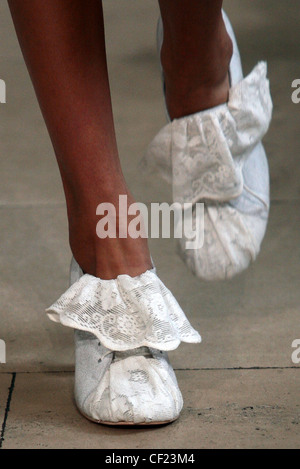 Tata Naka Londres Prêt à Porter Printemps Été Close up detail jambes de mannequin portant des chaussures de dentelle blanche à froufrous Banque D'Images