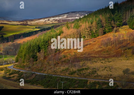 Une tempête de rupture révèle une mince couche de neige sur les collines Moorfoot. La célèbre forêt Glentress est visible au premier plan. Banque D'Images