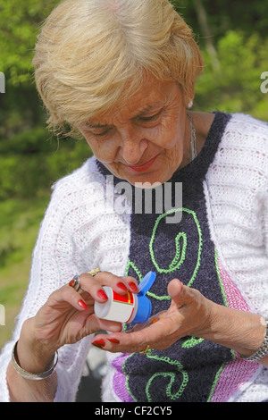 Senior woman prendre les pilules d'une bouteille dans un parc. Banque D'Images